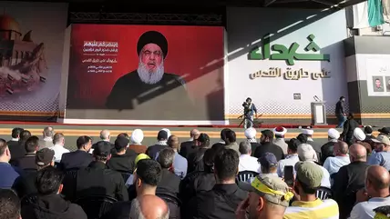Hezbollah leader Hassan Nasrallah seen on a screen addressing a crowd of supporters