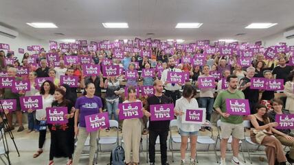 A group of Jews and Arabs hold up pink placards with white writing: the Hebrew slogan translates as 'together'