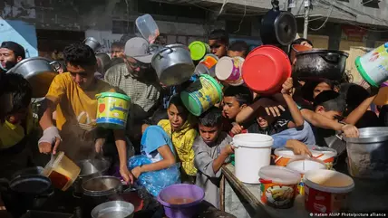  أطفال غزة باتوا يعيشون في ظل ظروف صعبة من نقص الاحتياجات الأساسية من ماء وغذاء ودواء. (image: Hatem Ali/AP Photo/picture alliance) Children holding buckets scramble for food handouts in Rafah, southern Gaza