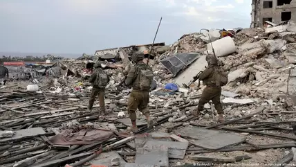 Three Israeli soldiers, armed and in fatigues, walk through rubble in the Gaza Strip 