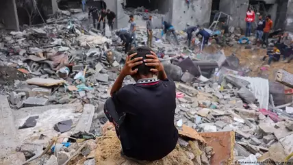 Gaza Strip: a boy sits desperately in front of a pile of rubble