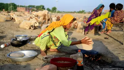 A young Pakistani woman kneels while making bread