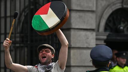 A man holding a traditional Irish drum painted to look like the Palestinian flag shouts and drums at a protest in Dublin, Ireland, 8 May 2024