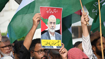 A man at a Palestine solidarity demo in Pakistan holds up a printed image of assassinated Hamas leader Ismail Haniyeh.