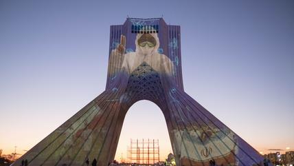 Das Portrait einer Krankenschwester im Schutzanzug wird auf das Azadi-Denkmal in Teheran projiziert.