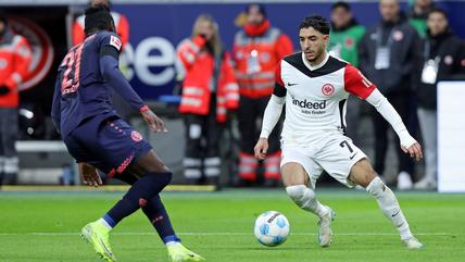Two football players close up, one attempts to dribble round the other.
