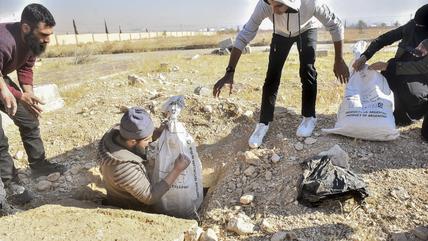 Arbeiter verpacken menschliche Überreste (Foto: picture alliance / Middle East Images | F. Itani)