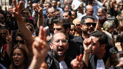 Lawyers protest against the arrest of their colleagues. Tunis, May 2024 (Photo: Picture Alliance / DeFodi Images | H. Mrad) Men wearing lawyers' gowns protest in a crowd.