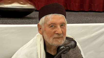 صورة مقربة للشيخ بشير جالسًا أمام الميكروفون