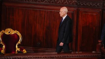 A man walks towards a gold-plated chair.