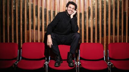 رجل يرتدي ملابس سوداء ويجلس على كرسي.