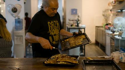 Ein Mann in einer Küche verteilt Essen.