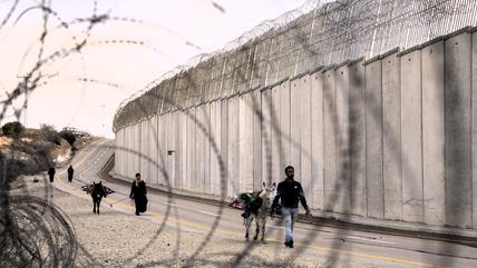 Palestinian farmers walk next to the Israeli separation barrier after the Israeli army allowed them to cross from the West Bank village of Beit Awwa to harvest olives on their land near the Israeli community of Shekef, Wednesday, Oct. 26, 2022.