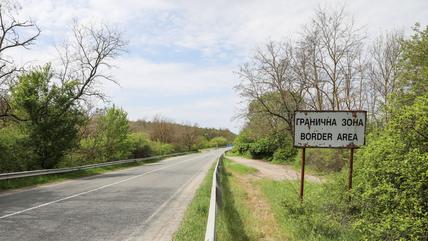 Eine Straße, rechts davon steht ein Schild mit der Aufschrift "Grenzregion" auf Englisch und Bulgarisch.