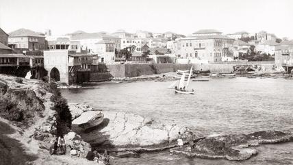 Black and white image of the Beirut seafront, with a sailing boat in the centre.