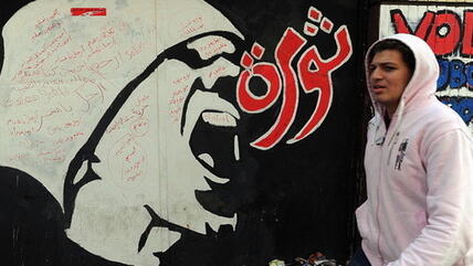 A young man walks past graffiti that reads 'revolution' in downtown Cairo (photo: dpa)