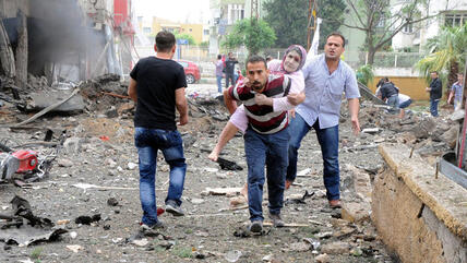 People help victims after an explosion in Reyhanli District, Hatay, Turkey, 11 May 2013. At least 13 people were killed and 22 wounded following explosions on 11 May in southern Turkey near the Syrian border (photo: picture-alliance/dpa)