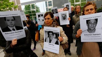 Demonstrators hold pictures of the victims of the NSU terror in front of the courthouse (photo: Reuters/Kai Pfaffenbach)