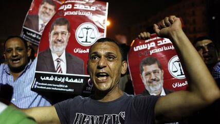 Anhänger der Muslimbruderschaft tragen auf einer Demonstration Plakate mit dem Foto von Präsident Mursi und der Aufschrift "Das Volk will den Aufbruch"; Foto: AP