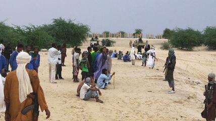In this Sunday, Sept. 16, 2012 photo, armed fighters from Islamist group Ansar Dine stand guard between onlookers and the area where Ansar Dine was preparing to amputate the hand of a young man found guilty of stealing rice, in Timbuktu, Mali (photo: AP)