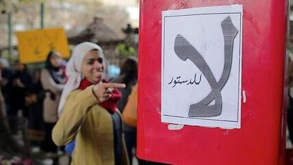 ناشطة تشير إلى لوحة مكتوب عليها: ''لا للدستور''. د ب أ