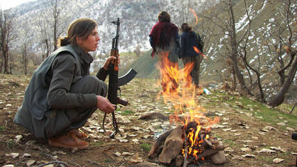 A member of the PKK warms herself by the fire at a camp in the Qandil mountains near the Turkish border with northern Iraq (photo: AP)