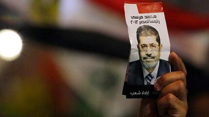 A man holds up an election leaflet, picturing Mohammed Morsi (photo: Reuters)
