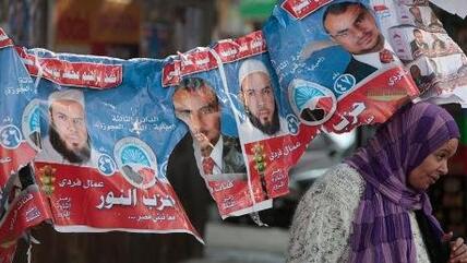 An Egyptian woman passes under electoral posters with pictures of candidates of the Salafist Al-Nour party (photo: AP/dapd)