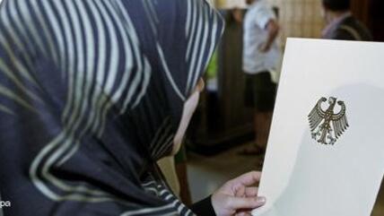 Muslima mit Kopftuch in Deutschland liest Ausz&uuml;ge aus einem Gesetzestext; Foto: dpa