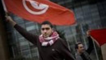 متظاهر تونسي ضد نظام بن علي يحمل علم بلاده. الصورة: AP