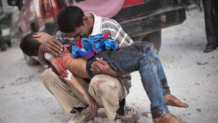 والد يحمل ابنه القتيل برصاص قوات الجيش السوري. أ ب