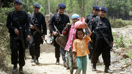 Indonesian Shia Muslims are escorted by police officers as they flee their village following sectarian violence in August 2012 (photo: picture-alliance/dpa)