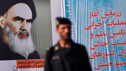An Iranian police officer standing in front of a poster of the Grand Ayatollah Khomeini in Tehran (photo: mehrnews)