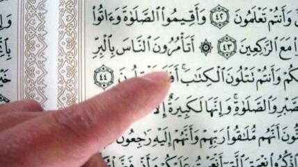 A finger pointing at verses of the Koran (photo: Ulrike Hummel/DW)