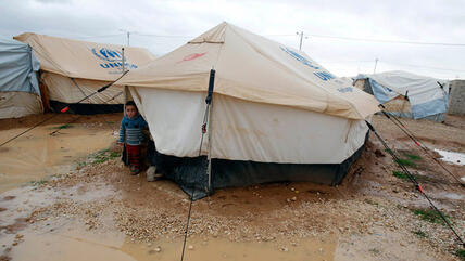 A Syrian refugee boy looks out of his parents' tent after heavy rain at the Al-Zaatari refugee camp, Jordan near the border with Syria (photo: REUTERS/Ali Jarekji)