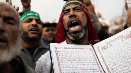 أحد أنصار الرئيس محمد مرسي يرفع القرآن الكريم عالياً في إحدى المظاهرات. أ ف ب