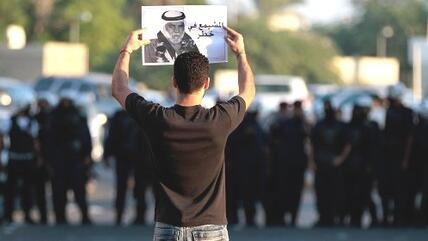 Riot police watch as an Bahraini anti-government protester holds up a picture of jailed political leader Hassan Mushaima with the words 'Mushaima is in danger', during a protest in Diraz, Bahrain, on Friday, Nov. 2, 2012 (photo: Hasan Jamali/AP/dapd)