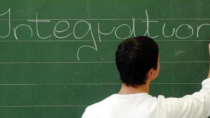 Schoolboy writes the word "Integration" on a chalk board (photo: dpa)