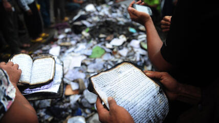 Bangladeshi people look at burnt religious literature, including the Holy Koran, in Dhaka following a clash between police and Islamists, 6 May 2013 (photo: MUNIR UZ ZAMAN/AFP/Getty Images)