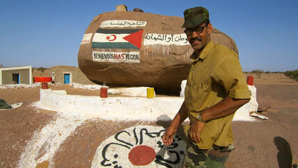 Ein Mann steht vor einem Grenzstein in Bir Lehlu, einer von der Frente Polisariao kontrollierten Stadt in der Westsahara; Foto: DW/Karlos Zurutuza