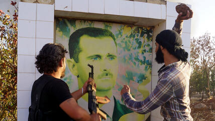Syrische Oppositionskämpfer zerstören ein Poster des Regimeführers Bashar Al-Assad, Anfang Juni 2015. Foto: DW/ AA/ I. Hariri