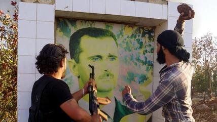 Syrian opposition fighters get ready to destroy a poster of President Bashar al-Assad, early June 2015 (photo: DW/AA/I. Hariri)