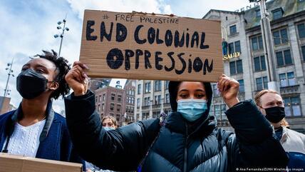 16 May 2021, Amsterdam, Netherlands: a Black woman seen holding a placard over her head against colonialism during a demonstration. In Amsterdam thousands of Dutch people gathered at the Dam Square in Amsterdam to condemn the Israeli attacks and the forced evictions of Palestinians from Sheikh Jarrah neighbourhood in occupied East Jerusalem.