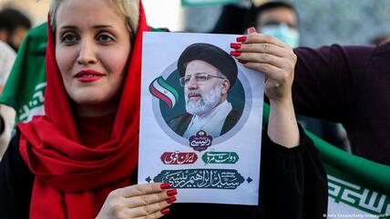 سيدة إيرانية تحمل صورة الرئيس الإيراني الجديد إبراهيم رئيسي بعد فوزه المتوقع بالانتخابات.  