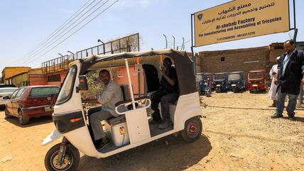Sudanese workers test a new electric tuk-tuk.