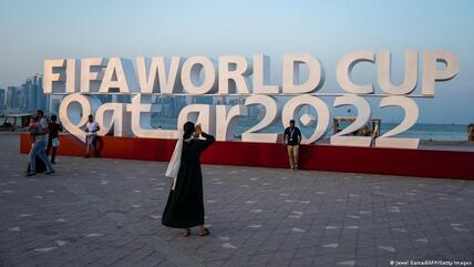 سياح أمام حروف إنكليزية كبيرة عن بطولة كأس العالم لكرة القدم 2022 في الدوحة - قطر.