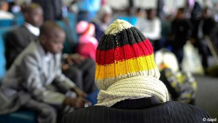 لاجئ من شمال إفريقيا يرتدي قبعة صوفية بألوان العلم الألماني يجلس في مبنى الركاب في مطار هانوفر.