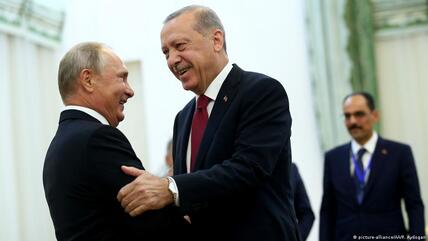 الرئيس الروسي بوتين والرئيس التركي إردوغان يُحَيِّي بعضهما بعضاً -ضاحكَيْنِ- في العاصمة الإيرانية طهران عام 2018.