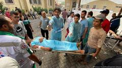 Two men hold a stretcher while medics administer treatment to a patient in the yard of Al-Ahli Baptist Hospital, Gaza City
