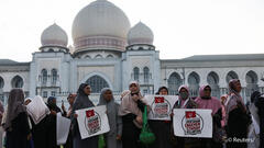 Muslim women hold placards as they stand in protest outside the Palace of Justice on the day the country's federal court delivers verdict in a constitutional case challenging the legality of some Islamic laws in Kelantan state, in Putrajaya, Malaysia